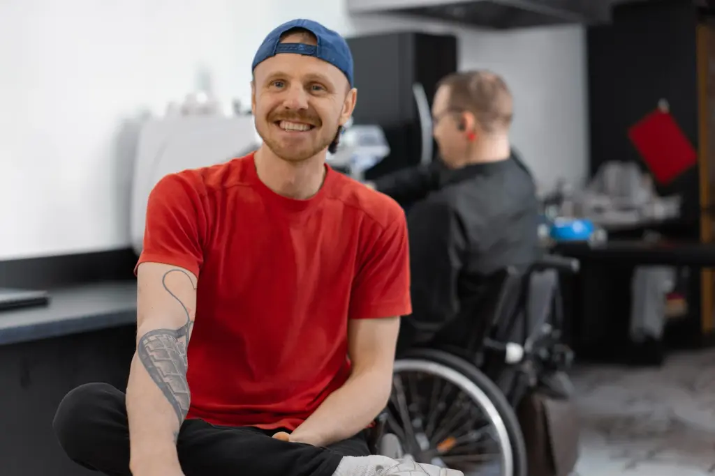 A support worker and a wheelchair user working together in a cafe kitchen