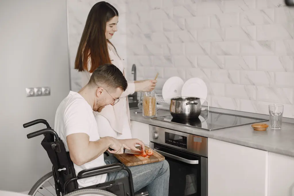 A man in a wheelchair and a housemate preparing a meal together