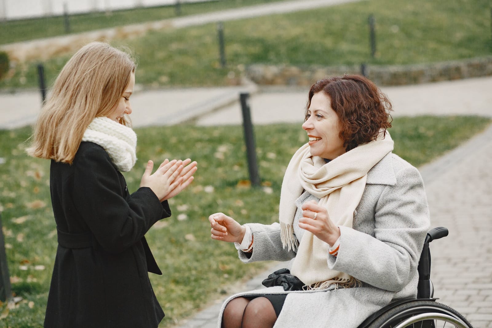 A support worker and a woman in her wheelchair laughing together outdoors